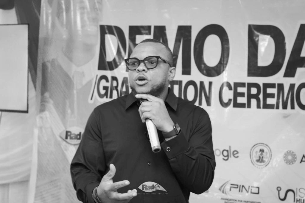 Ifunanya Onwughalu speaking into a microphone at a startup demo day
